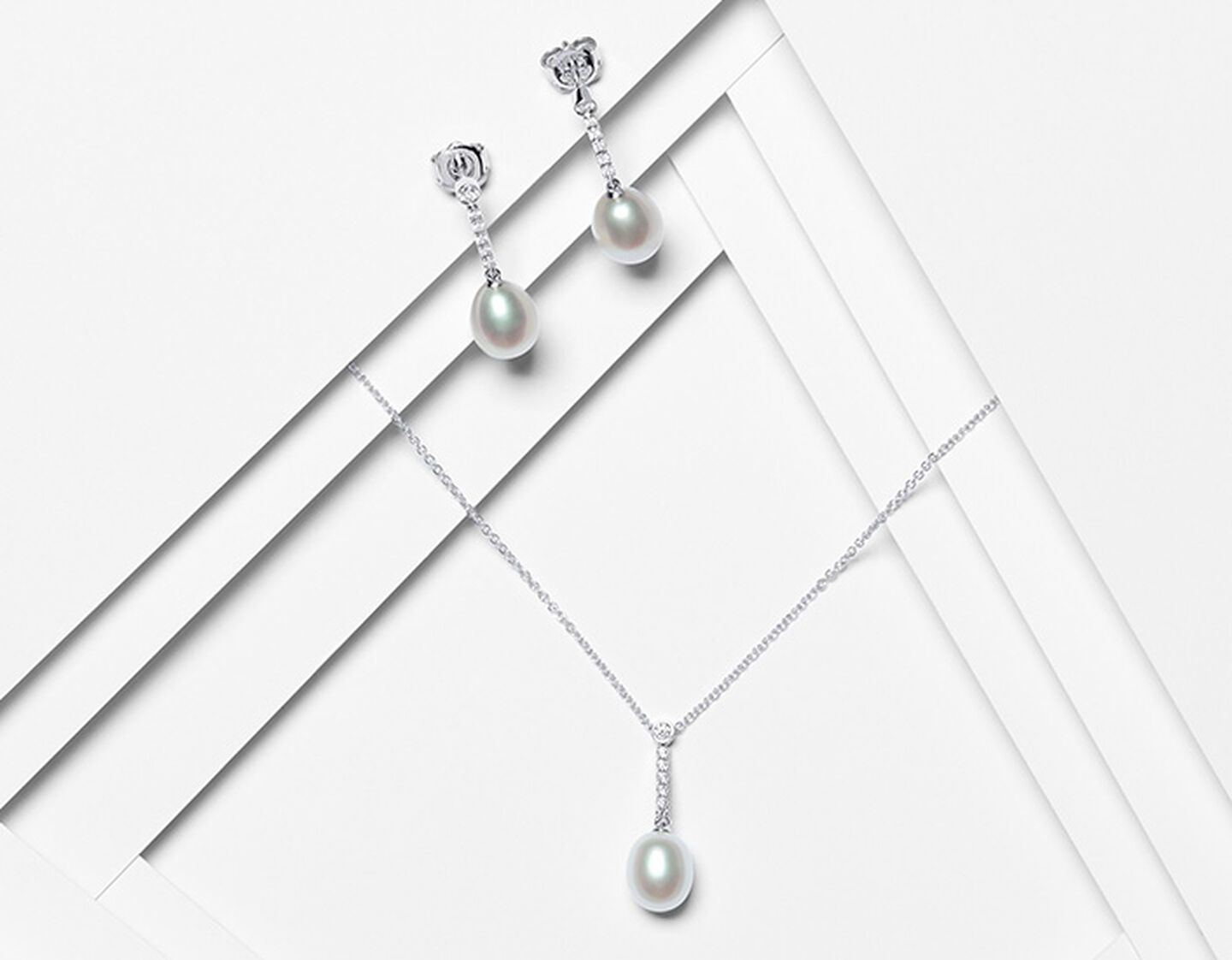 Birks Pearls earrings and necklace on a white layered background.